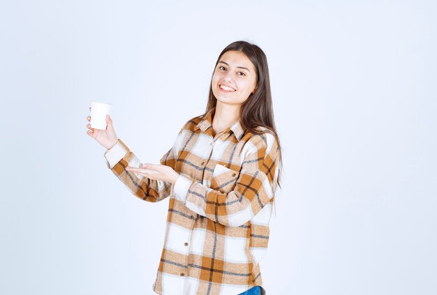 young girl with cup of tea feeling happy on white wall.