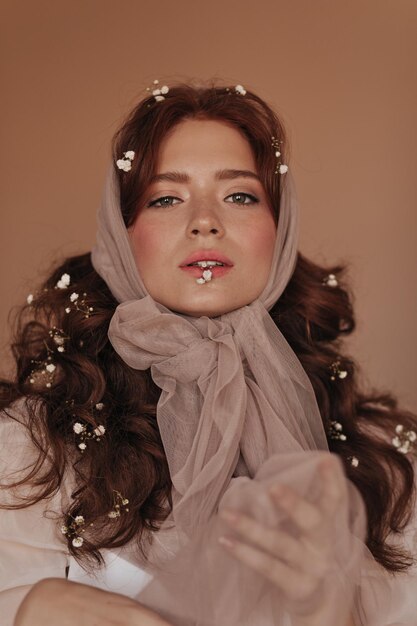 Young girl with green eyes holds small flower with her teeth Lady in headscarf poses with flowers in curly hair