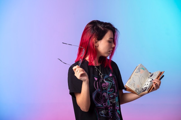 Young girl with pink hairs holding a sketchbook and checking it.