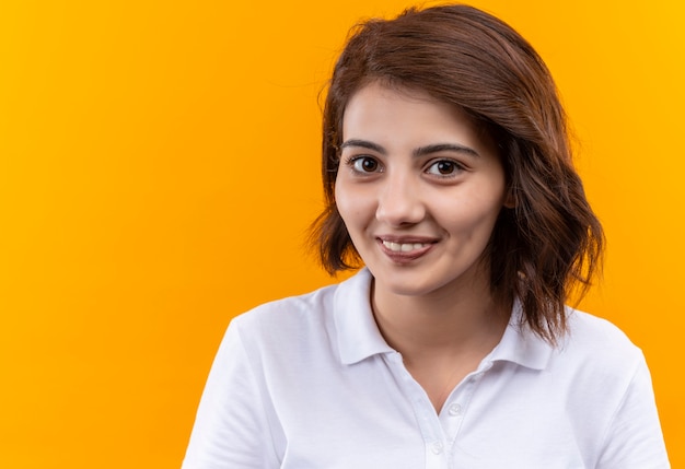 Young girl with short hair wearing polo shirt looking at camera with smile on face