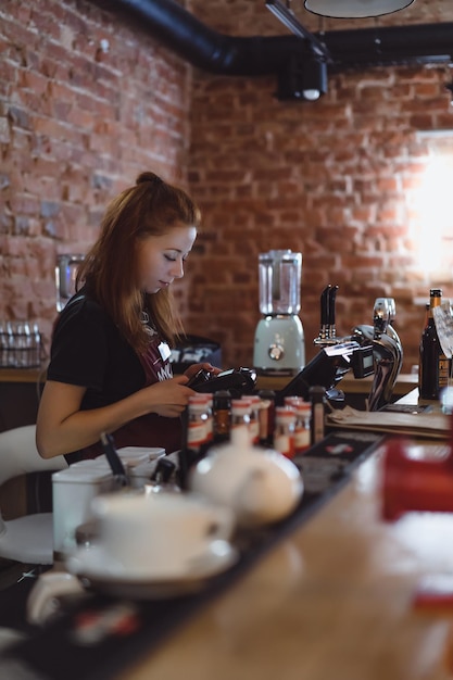 A young girl works in a cafe at the bar