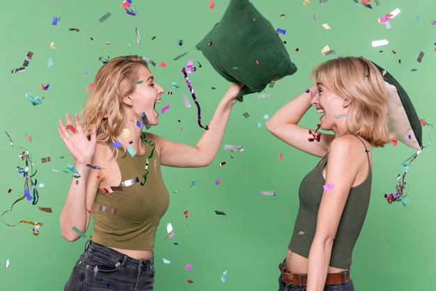 Free photo young girls having a pillow fight