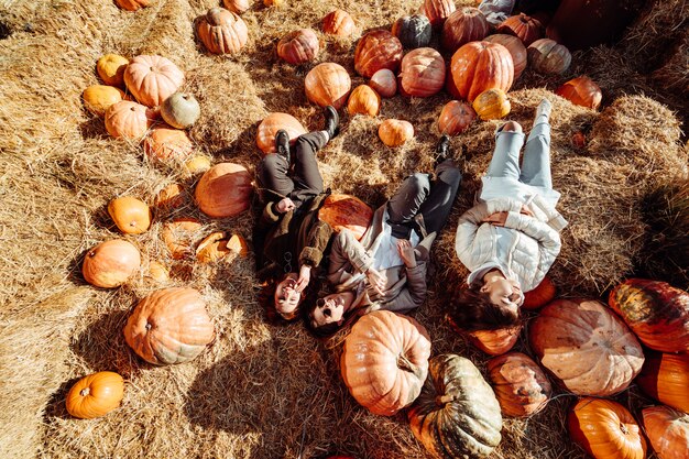 Young girls lie on haystacks among pumpkins