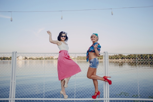 Young girls posing with one leg lifted on a white fence