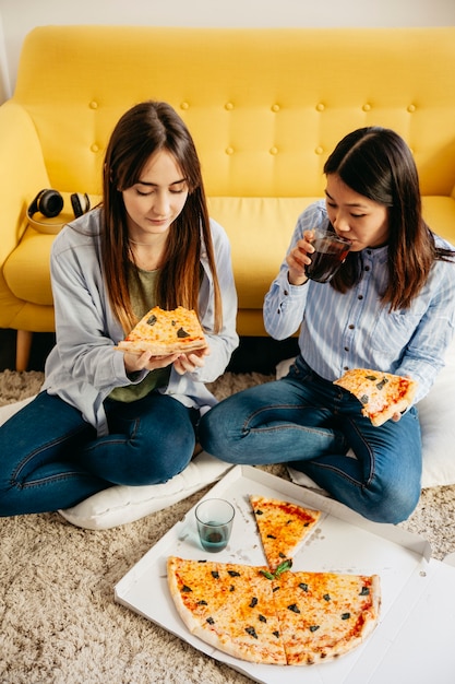 Free Photo young girls sharing pizza and chilling