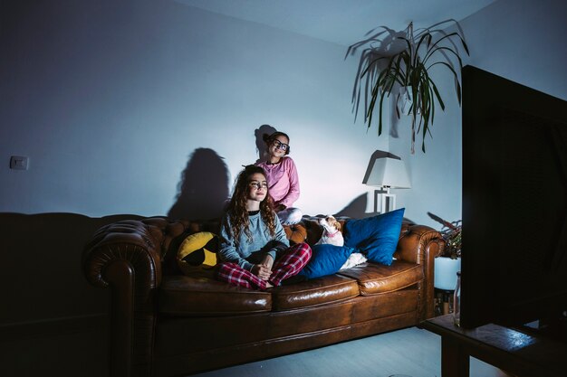 Young girls with dog watching TV