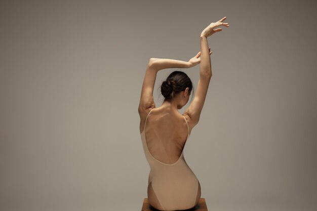 Young graceful tender ballerina on pastel wall