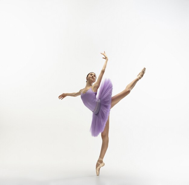 Young graceful tender ballerina on white wall