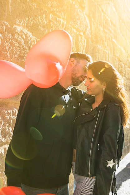 Free photo young guy hugging lady with balloons on street