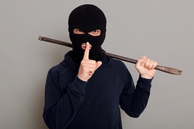 Free photo young guy robber man dressed in a black hoodie with masked face