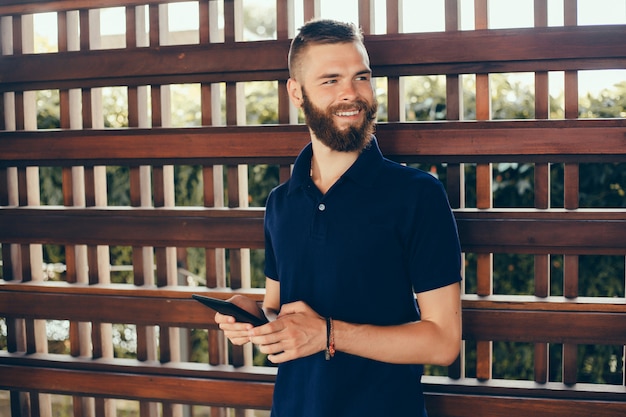 young guy with a beard works in a cafe, freelancer uses a tablet, does a project