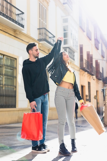 Young guy with packets holding upping hand of lady on street