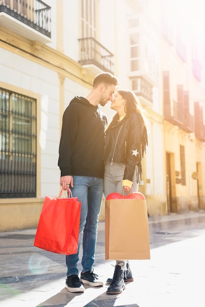 Young guy with packets kissing lady on street