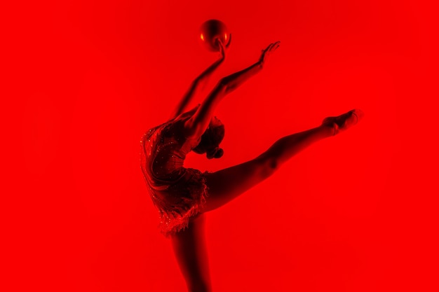 Free Photo young gymnastics athlete isolated on red studio wall