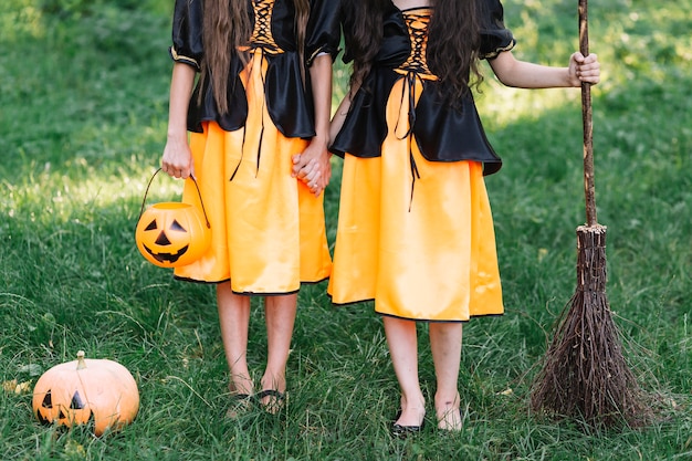 Free photo young halloween dressed girls with pumpkin and broom in woods