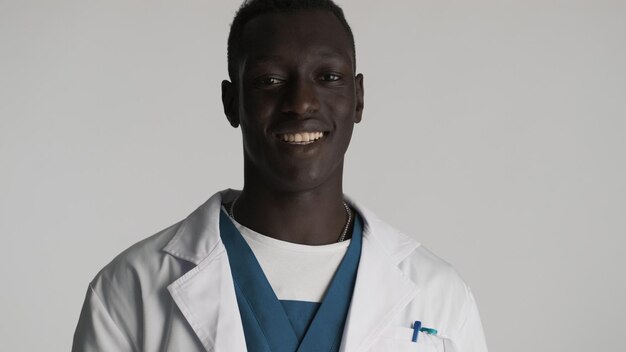 Young handsome African American male doctor looking happy smiling on camera over white background