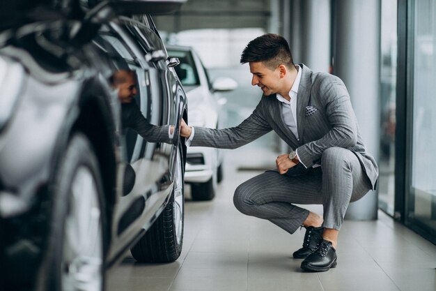 Young handsome business man choosing a car in a car showroom