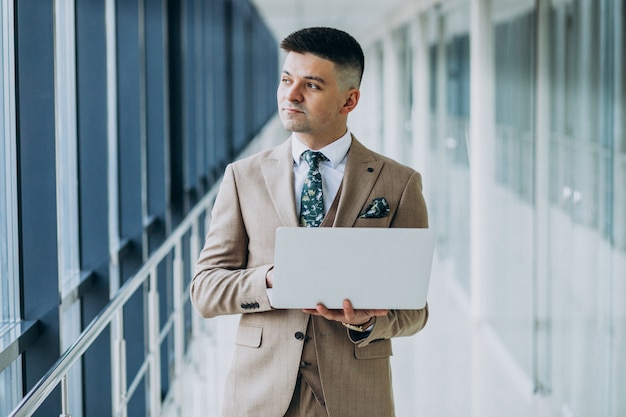 Free photo young handsome business man standing with laptop at the office