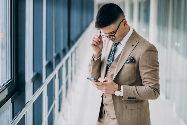 Young handsome business man standing with phone at the office