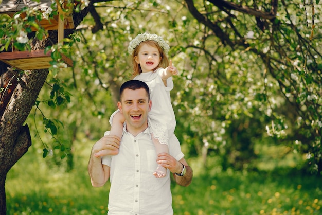 a young and handsome father playing with his little daughter in the summer park