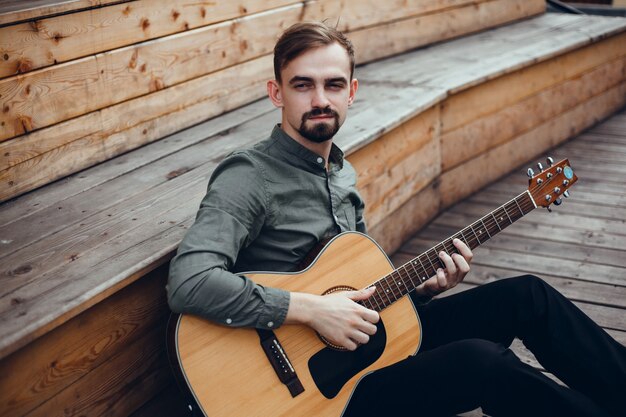 young handsome guy plays the guitar, picks up a chord, street musician