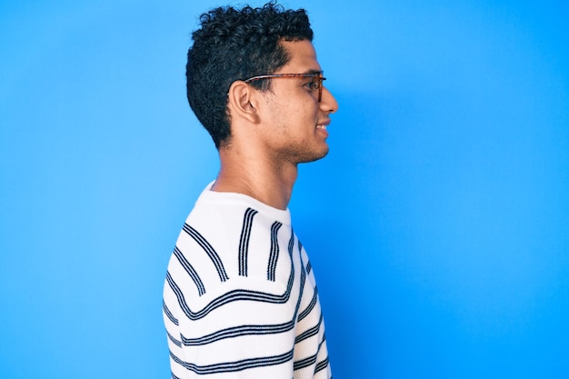 Free photo young handsome hispanic man wearing casual sweater and glasses looking to side relax profile pose with natural face with confident smile