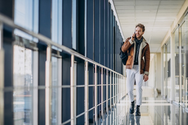 Free photo young handsome man at airport talking on the phone