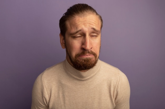 Free photo young handsome man in beige turtleneck with sad and hopeless expression standing over lilac wall