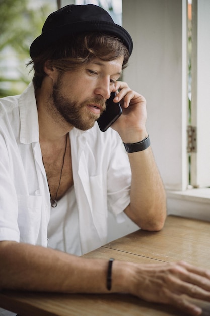 Free photo a young handsome man in a casual look calls on the phone, talks on the phone.