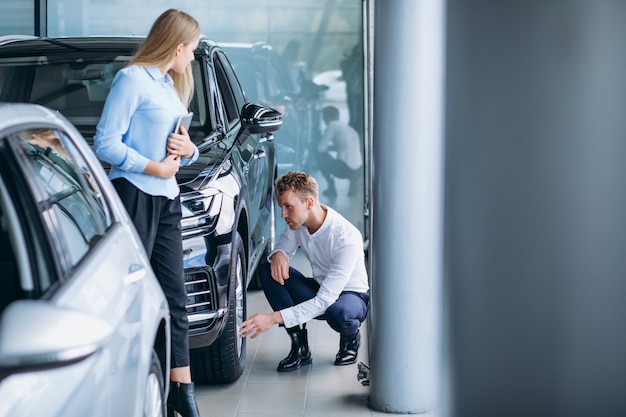 Young handsome man choosing a car in a car showroom