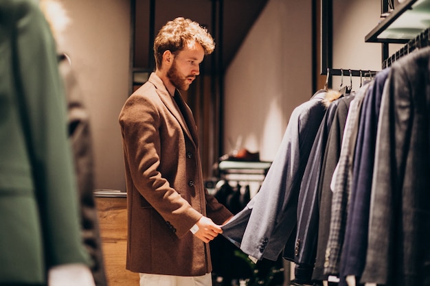 Free Photo young handsome man choosing cloth at shop