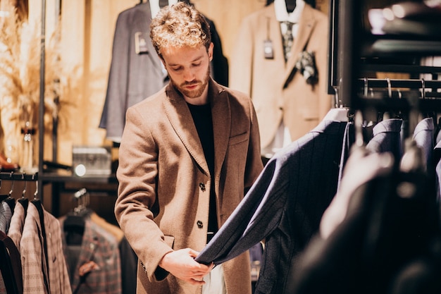 Young handsome man choosing clothes at shop