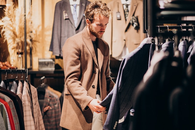 Young handsome man choosing clothes at shop