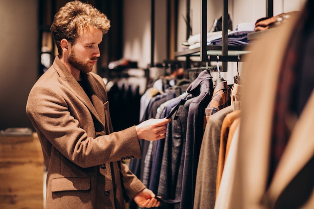 Young handsome man choosing clothes at shop