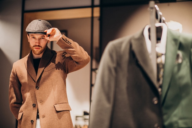 Free photo young handsome man choosing hat at the shop