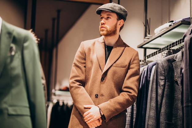 Free photo young handsome man choosing hat at the shop