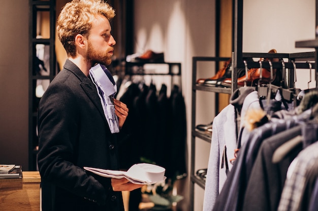 Free photo young handsome man choosing shirt at a shop