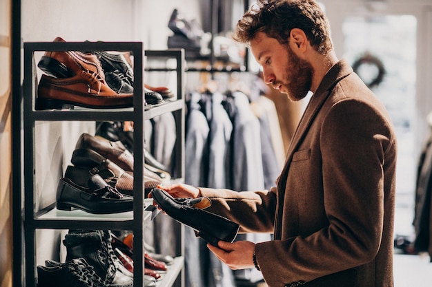 Young handsome man choosing shoes at a shop