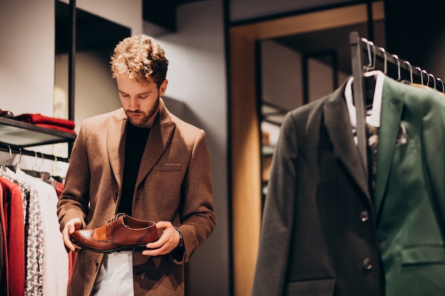 Free photo young handsome man choosing shoes at a shop