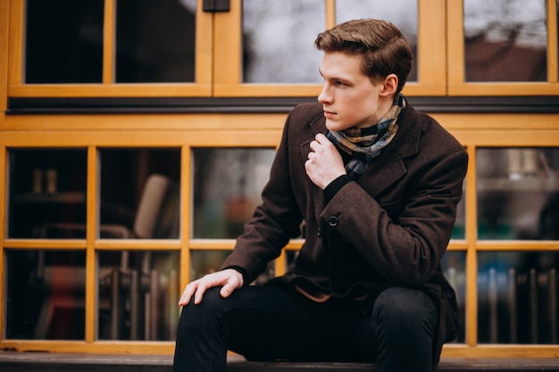 Young handsome man in a coat outside the street