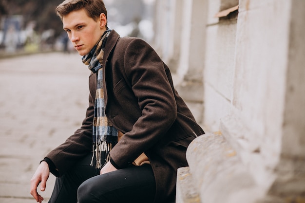 Free photo young handsome man in a coat outside the street