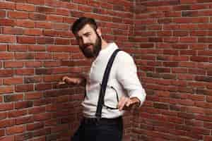 Free photo young handsome man dancing posing on brick wall.