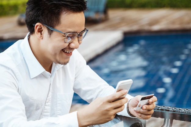 Young Handsome man enjoy shopping online on mobile phone with credit card.