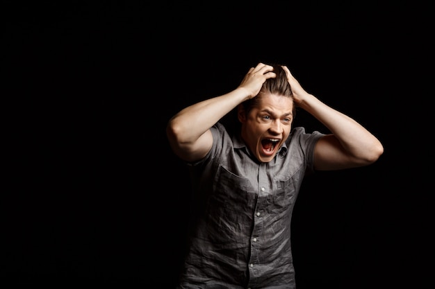 Free photo young handsome man grab his head, shouting