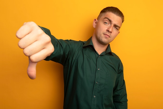 Free photo young handsome man in green shirt being displeased showing dislike