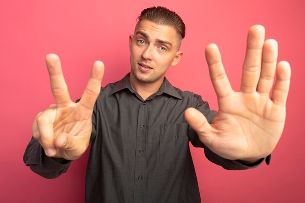 Young handsome man in grey shirt looking at front smiling confident showing number seven standing over pink wall