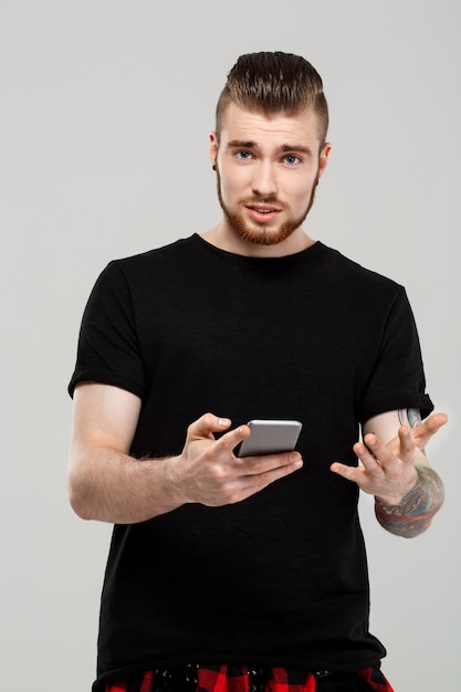 Free Photo young handsome man holding phone over grey wall.