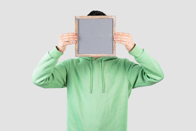 young handsome man in hoodie hiding empty frame