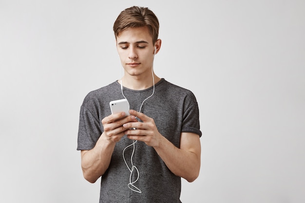 Young handsome man listens music in smartphone with earphones. Music app