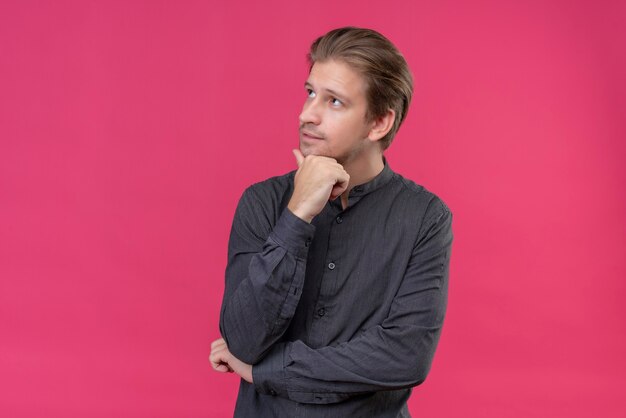 Young handsome man looking aside with hand on chin with pensive expression